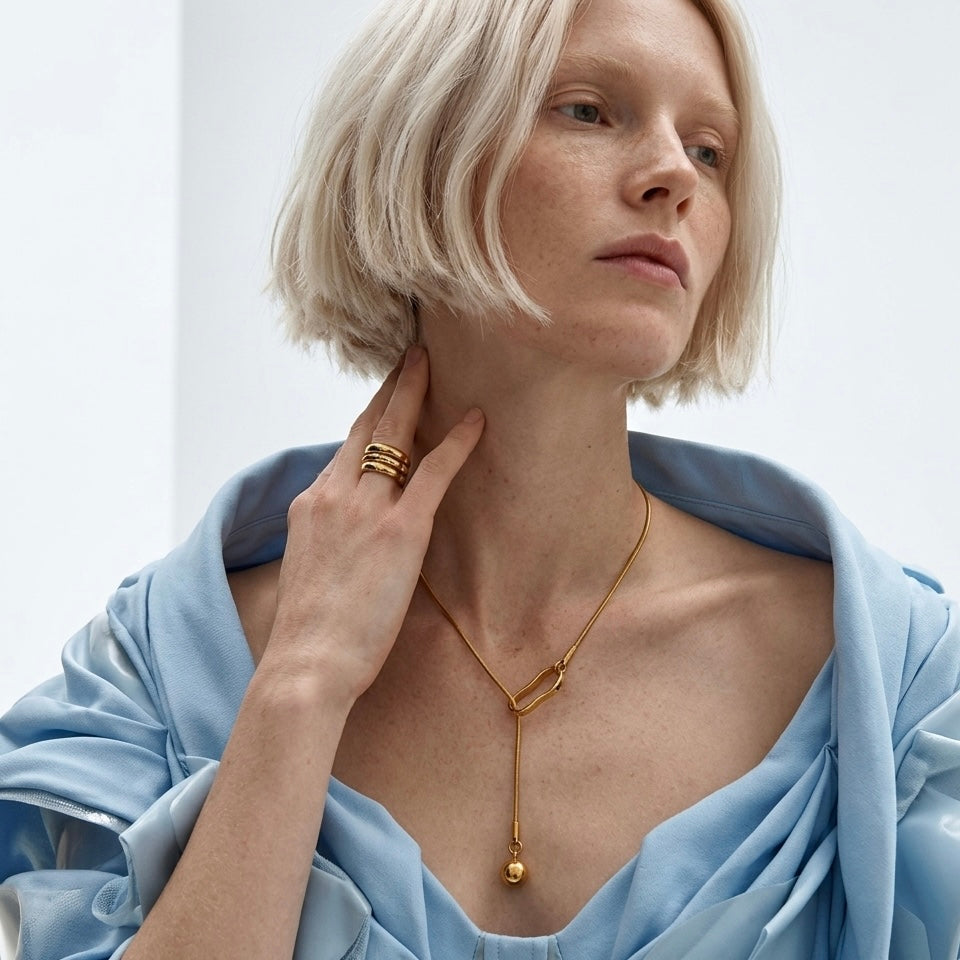 Close-up of the waterproof BEHI Temwoo Necklace, highlighting the sculptural lariat design and radiant golden glow.
