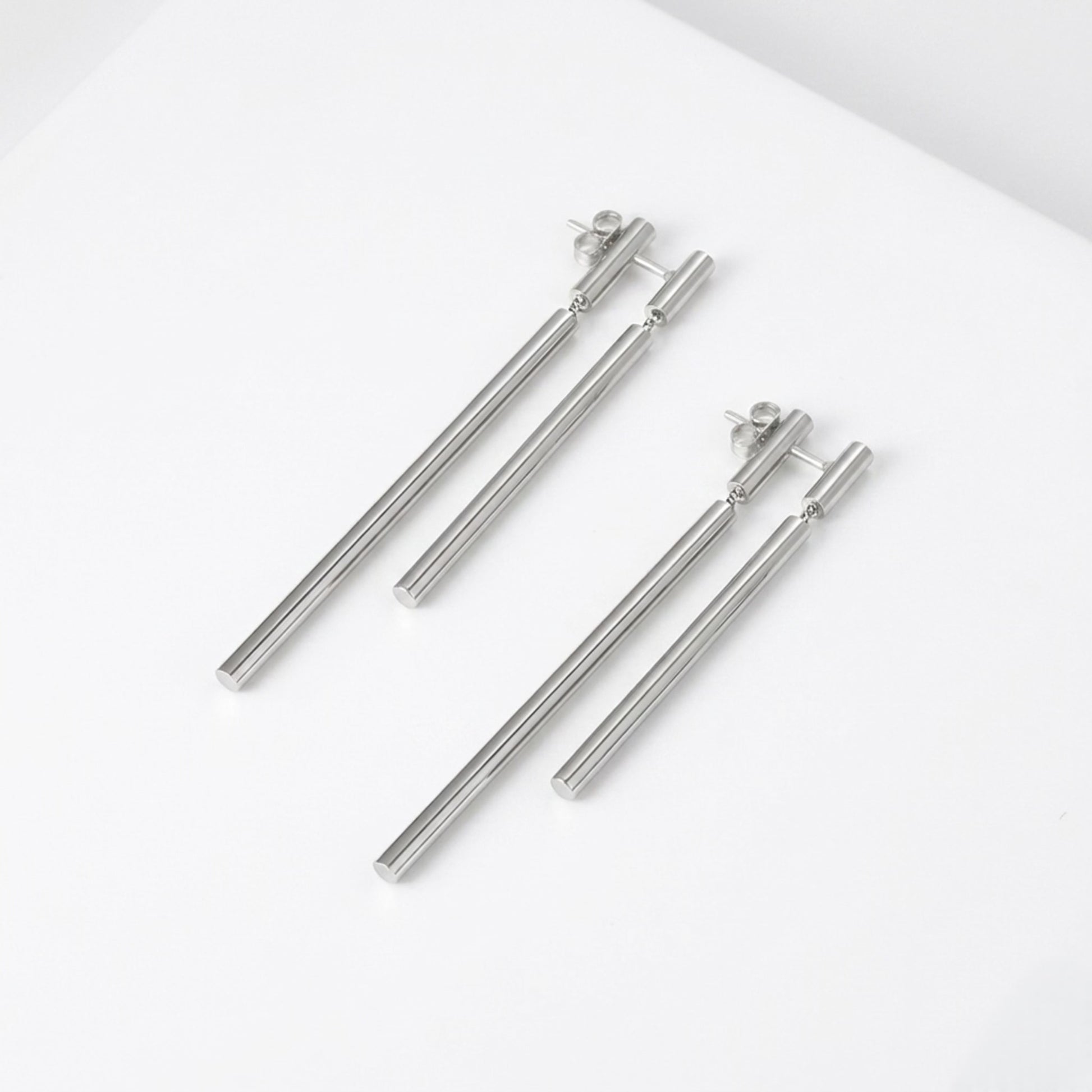 BEHI Deffi Earrings in silver finish, showcasing the sleek, waterproof, and hypoallergenic metallic triple-rod design.