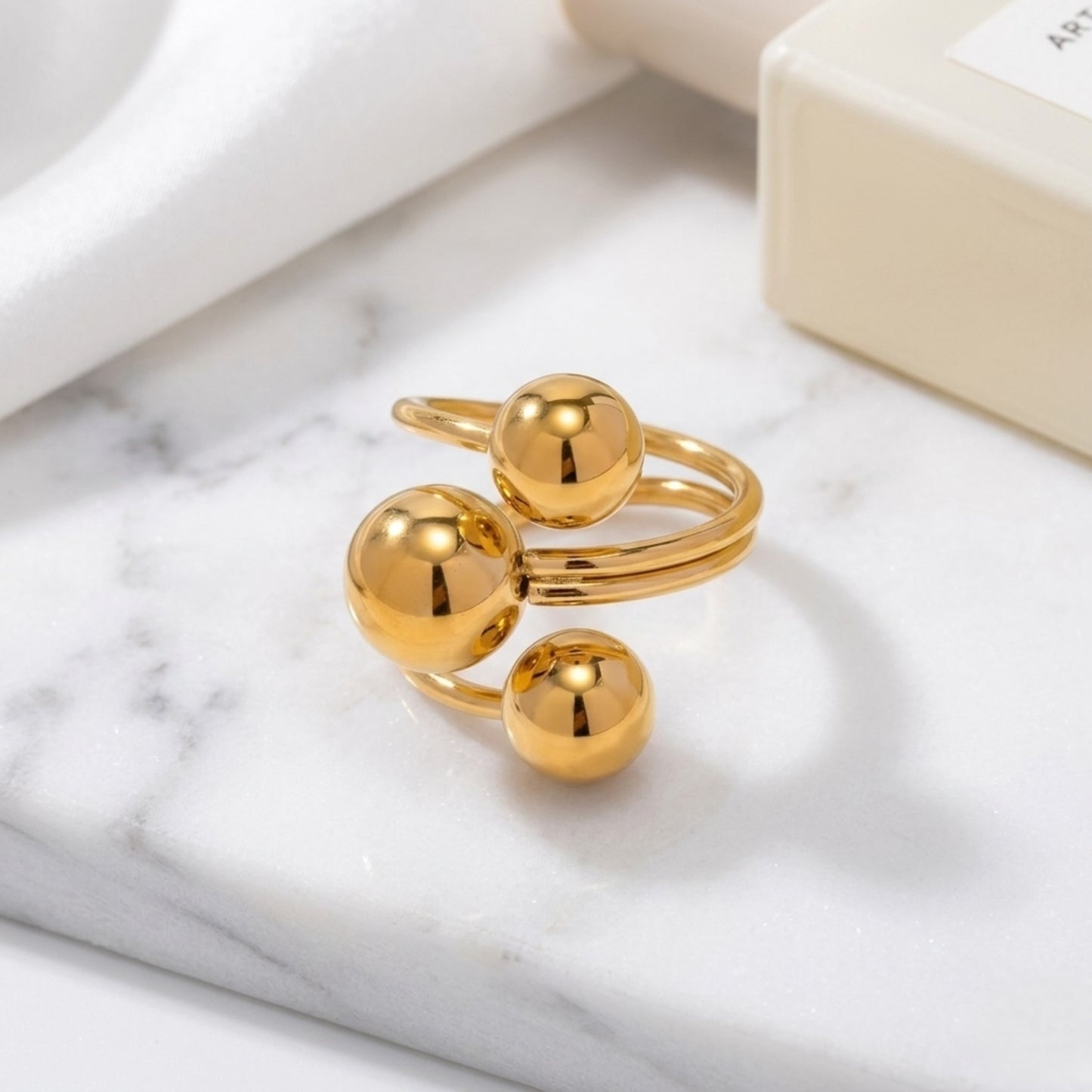 An angled perspective of the gold BEHI Mia Ring, emphasizing the smooth, high-polish texture of the triple-sphere band.