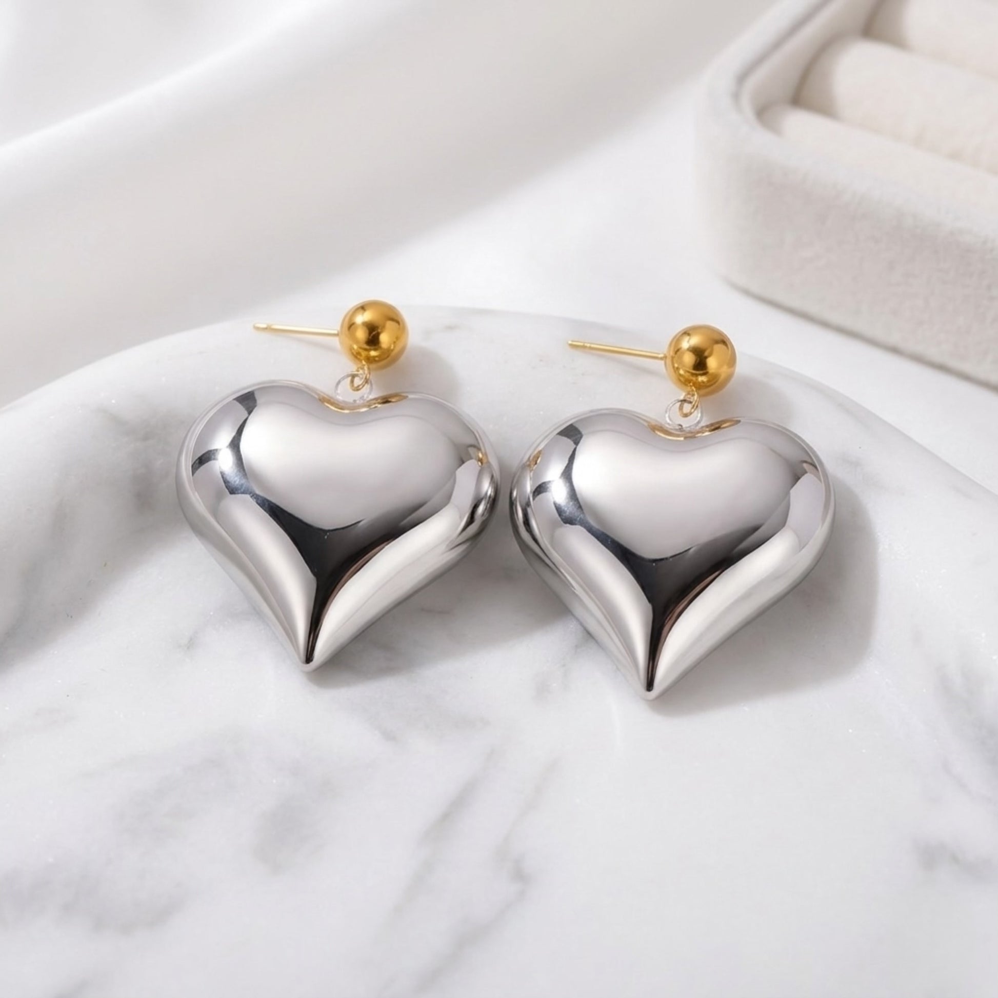 BEHI EMMA xl 18k PVD gold-plated stainless steel big heart-shaped earrings with a metallic silver finish and gold accents on the top part.