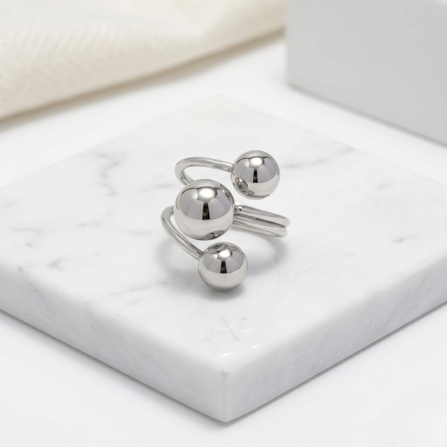 BEHI Mia Ring in silver finish resting on a clean surface, highlighting its sleek, waterproof, and hypoallergenic metallic shine.