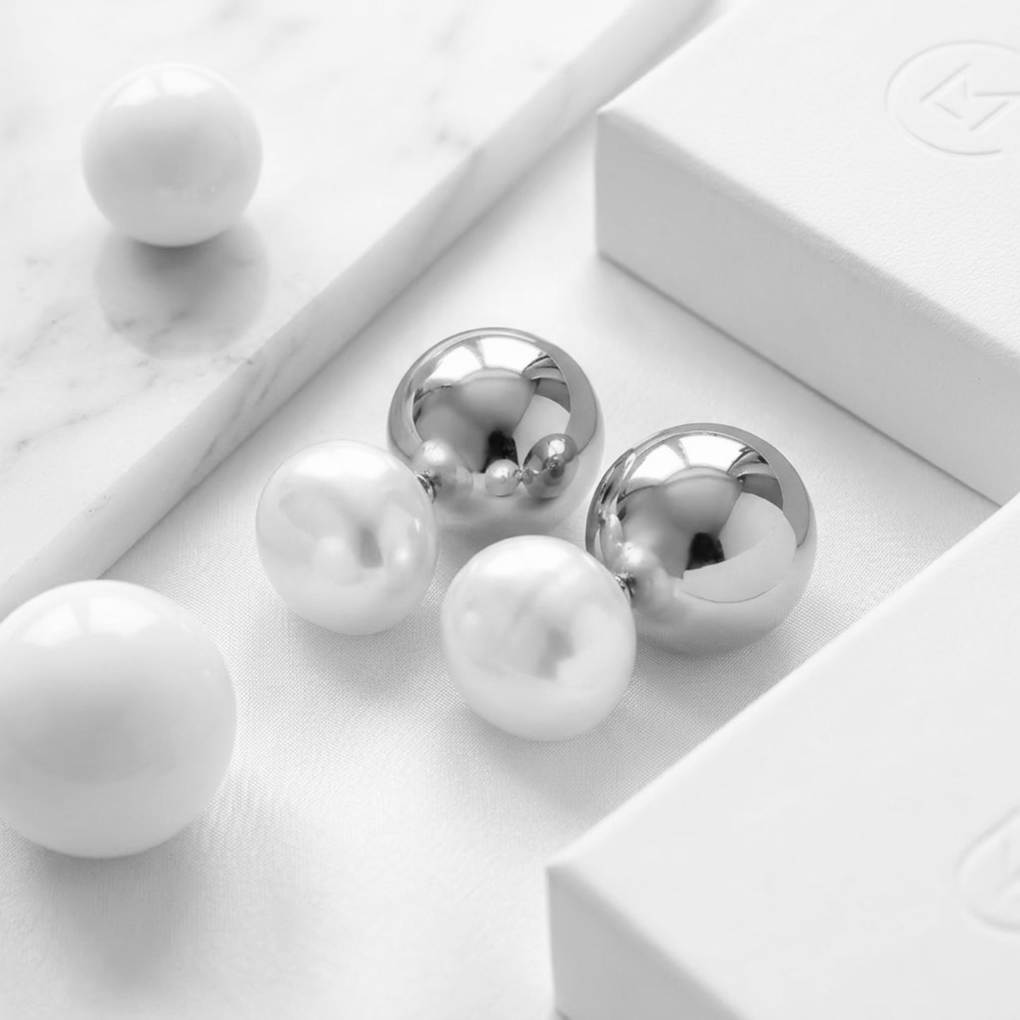 BEHI ROWA earrings featuring a 18k PVD gold plated small shiny silver sphere with an imitation pearl piece minimal design