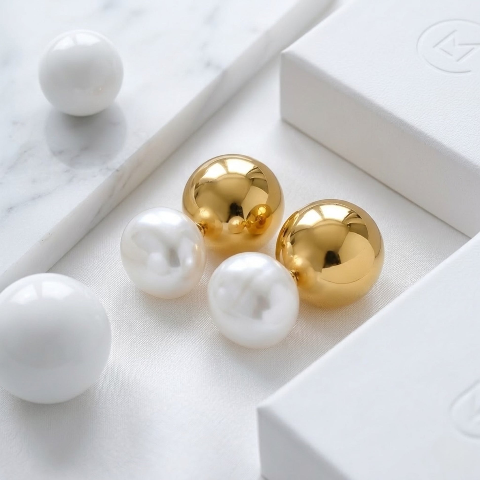 BEHI ROWA earrings featuring a 18k PVD gold plated small shiny sphere with an imitation pearl piece dual sphere