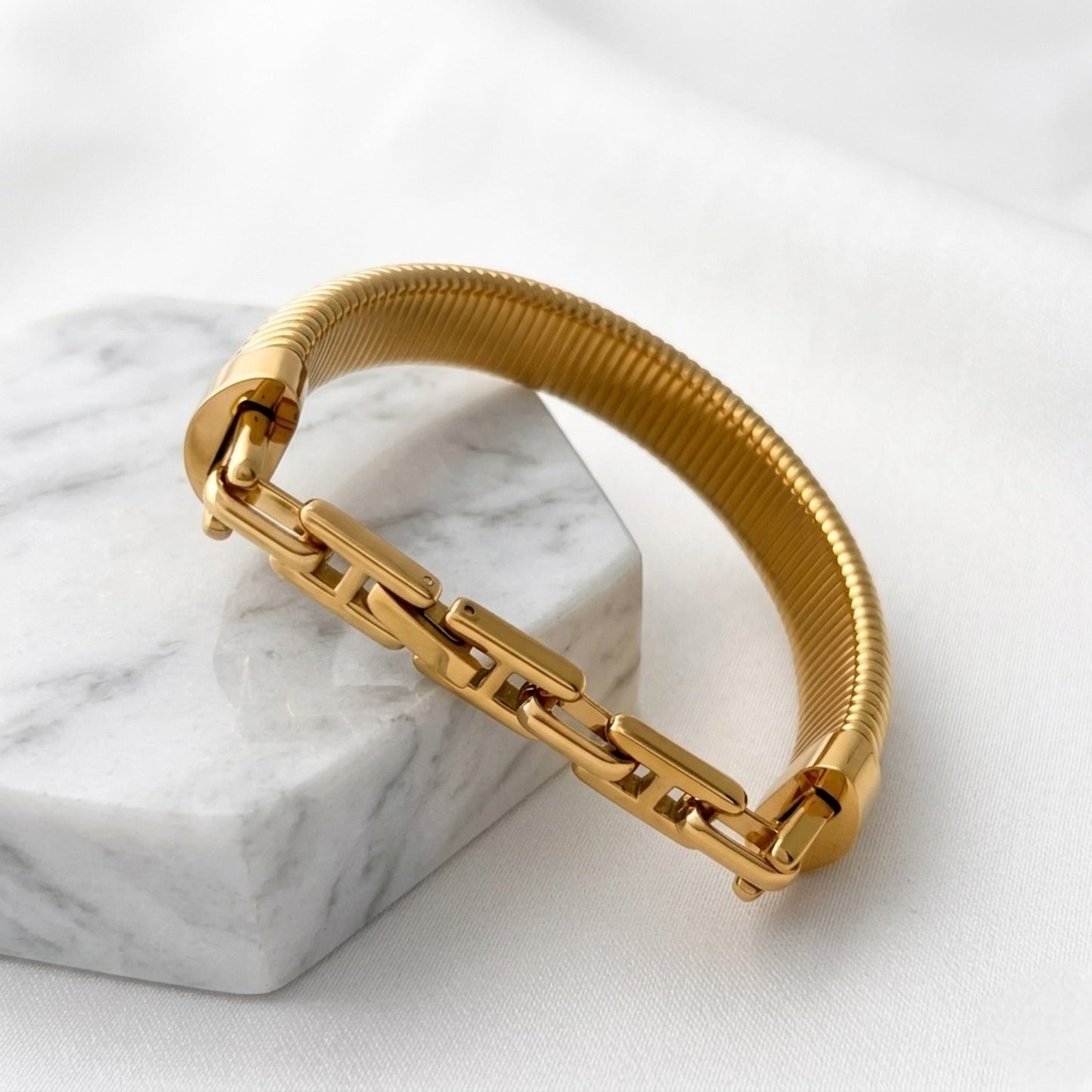 BEHI MILANO Almond Bracelet gold detail — wide ribbed bangle texture close-up, 18k PVD-coated stainless steel, polished gold finish