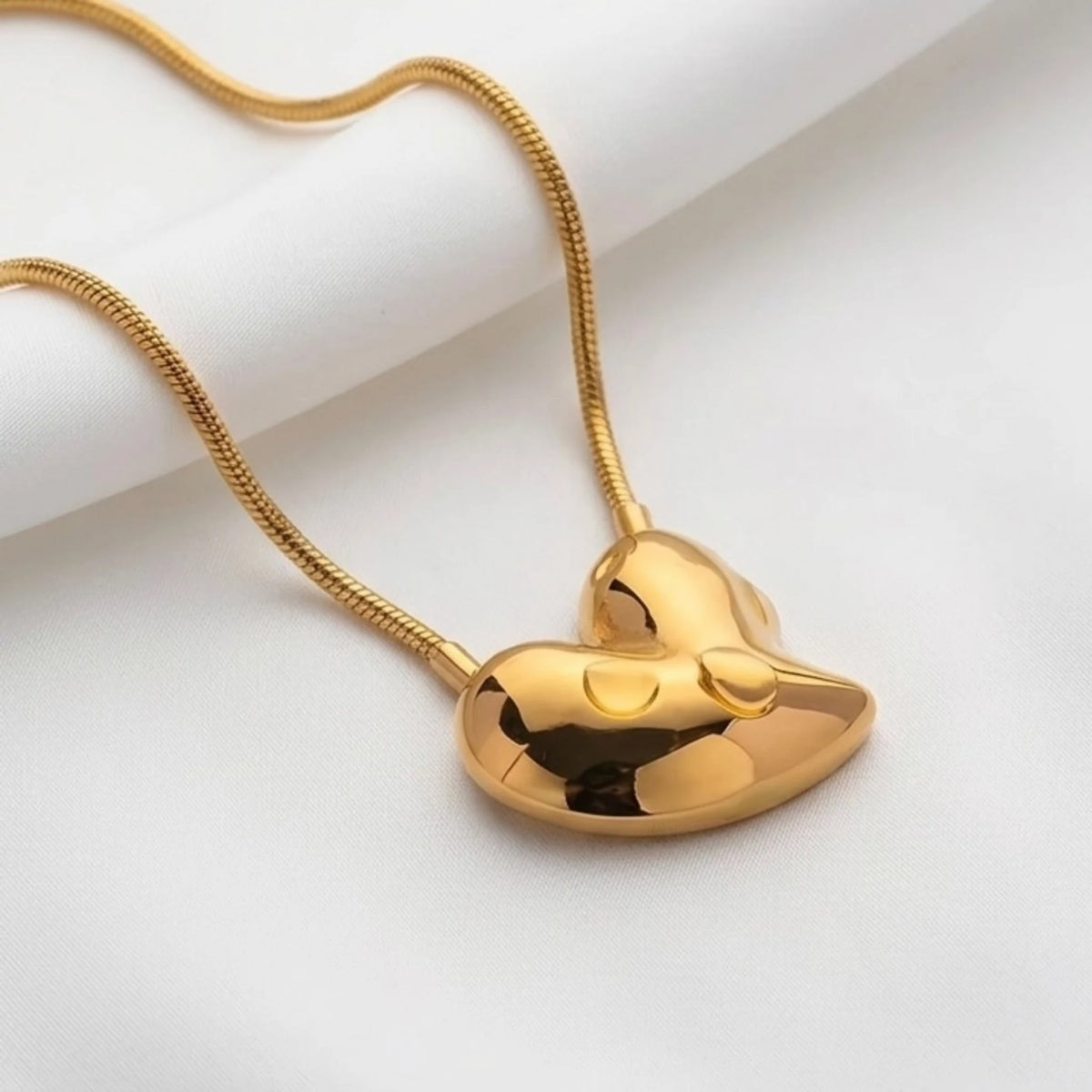 BEHI MILANO Amorino Necklace — detail view of polished gold heart pendant