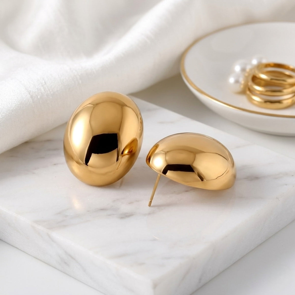 BEHI MILANO Annarita Earrings — 18k gold chunky oval dome earrings on white marble tray