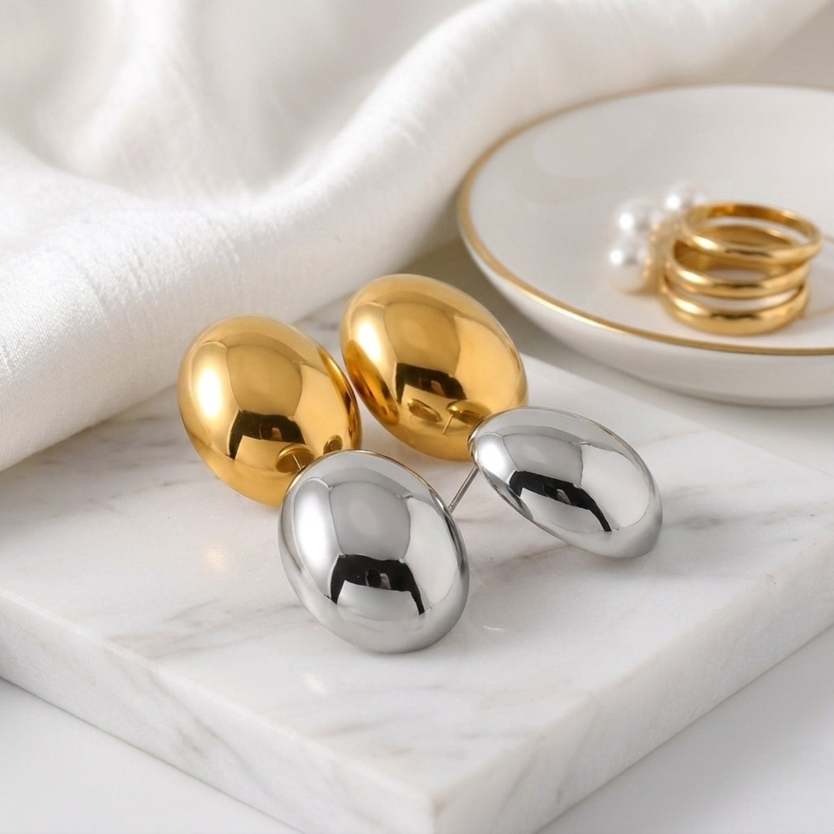 BEHI MILANO Annarita Earrings — side-by-side comparison of 18k gold and silver oval dome studs