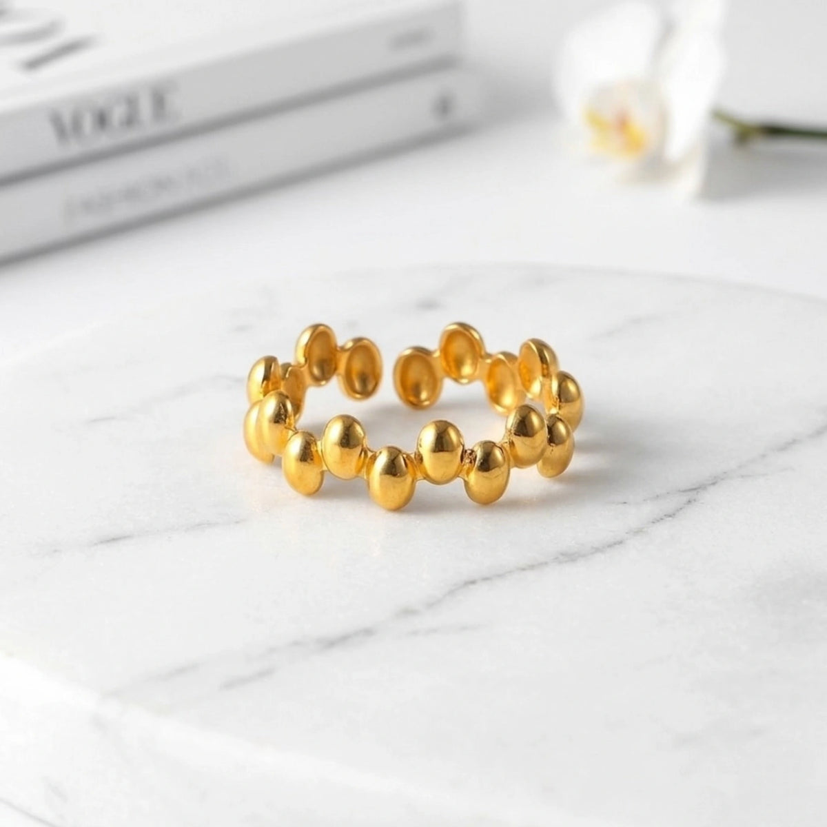 BEHI MILANO Anya Ring — 18k gold beaded ring styled on white marble with magazine backdrop