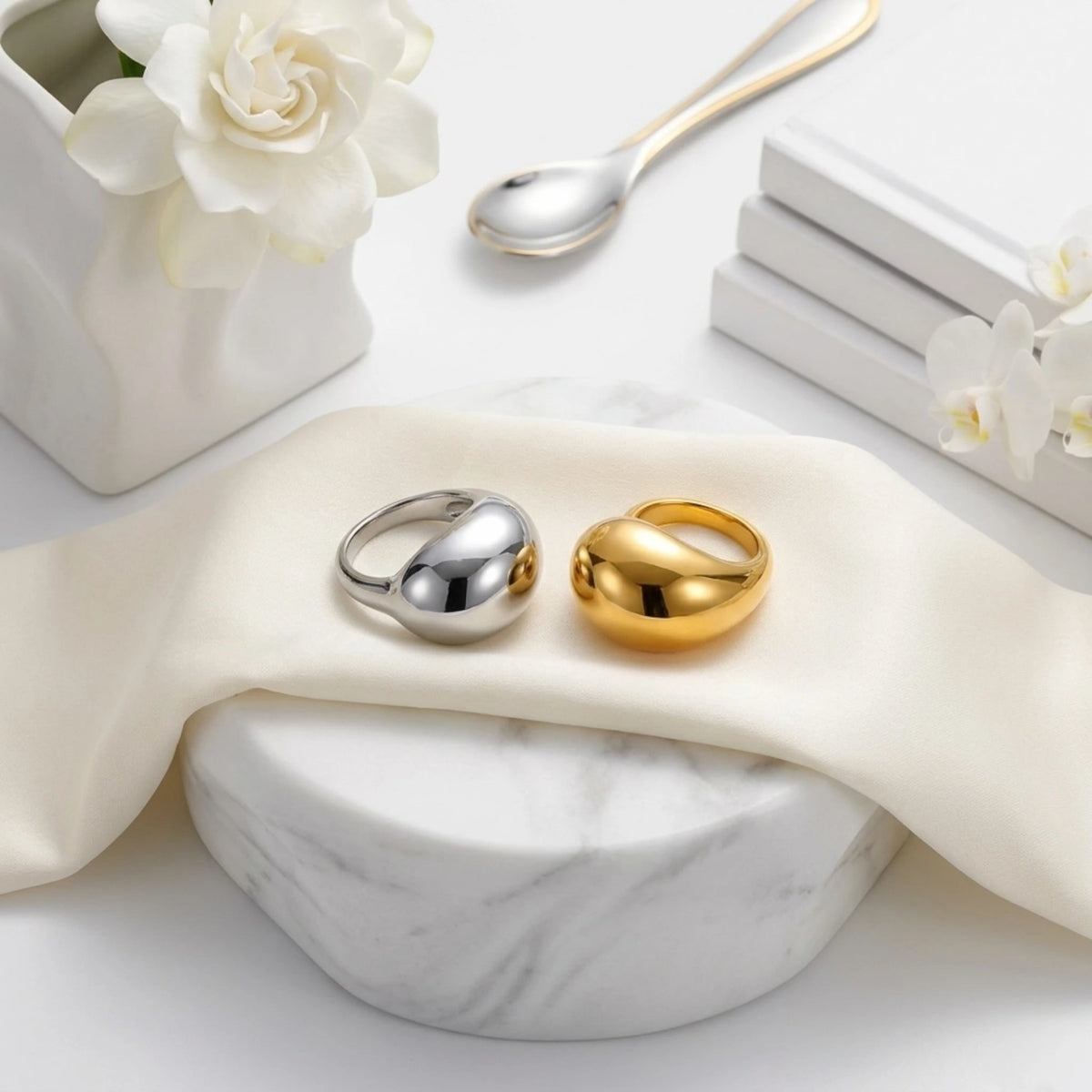BEHI MILANO Archana Ring — detail shot of gold and silver liquid dome rings on draped white silk