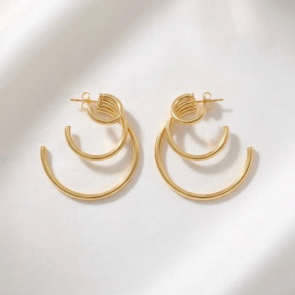 BEHI MILANO Ariel Earrings — pair of 18k gold multi-ring hoop earrings on white silk