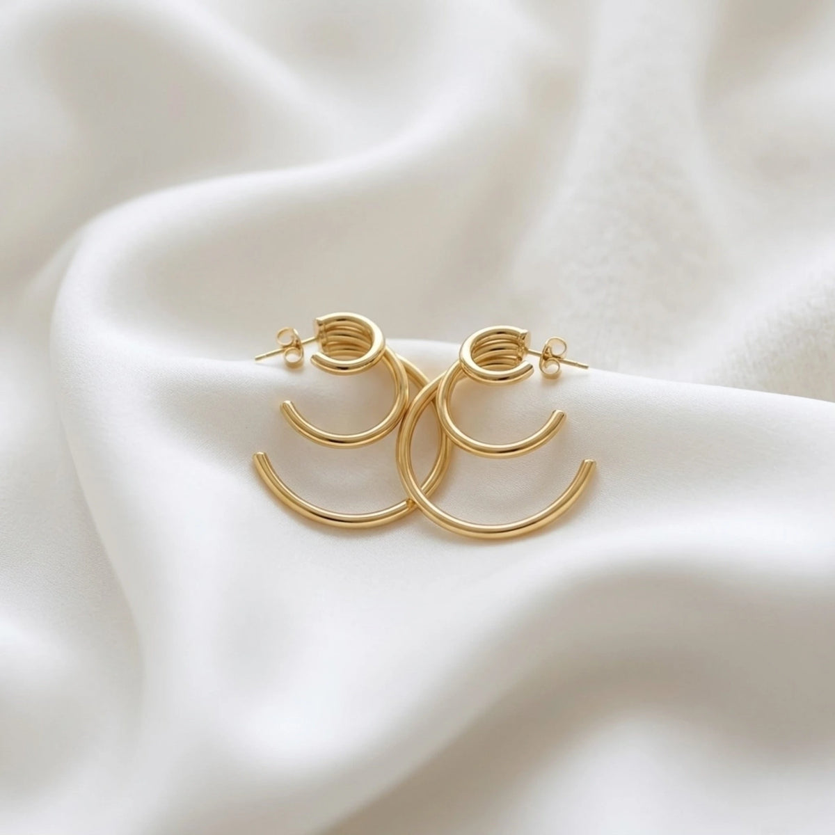 BEHI MILANO Ariel Earrings — detailed view of post backs and open rings on soft white fabric