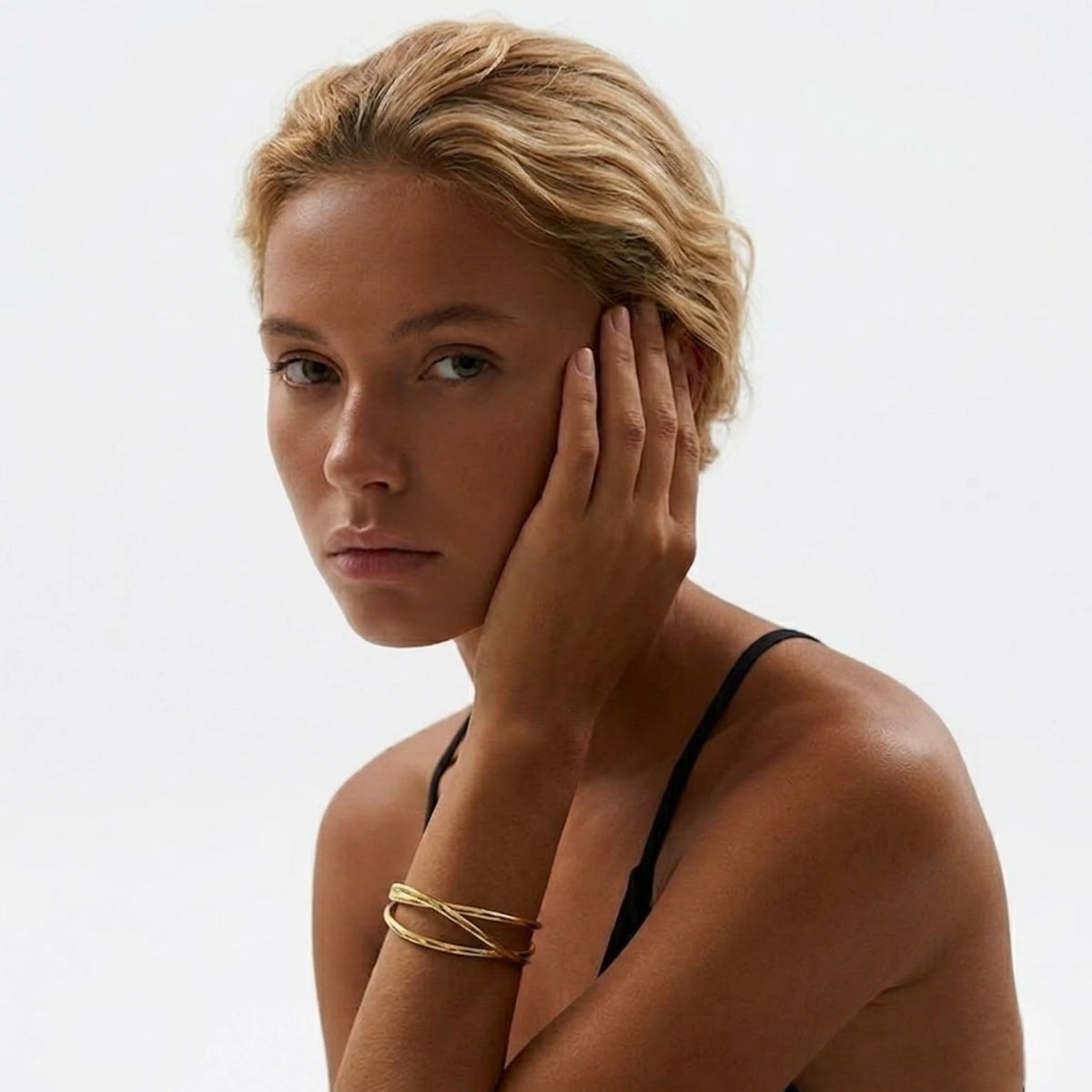BEHI MILANO Ariella Bracelet — close-up of 18k gold crisscross cuff bracelet on model's wrist