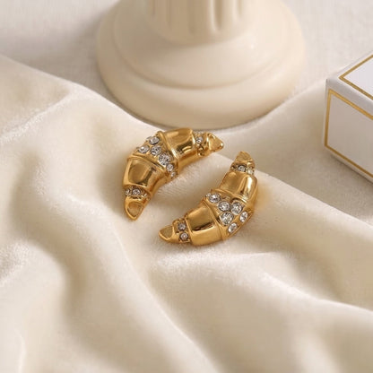 BEHI MILANO Aris Earrings — pair of 18k gold zircon croissant earrings on soft white silk fabric