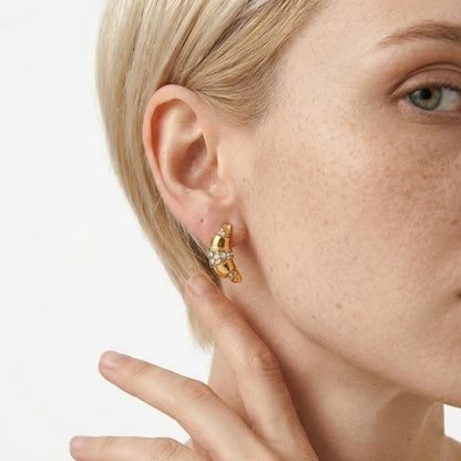 BEHI MILANO Aris Earrings — close-up view of croissant gold zircon stud earring on model's ear
