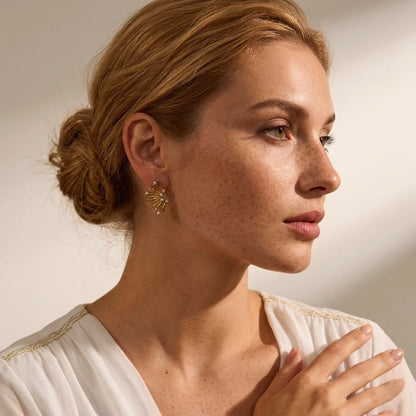 BEHI MILANO Artyman Earrings — model with low hair bun wearing gold textured petal earrings