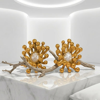 BEHI MILANO Artymanos Earrings — pair of 18k gold-plated crystal earrings placed on natural wood branch
