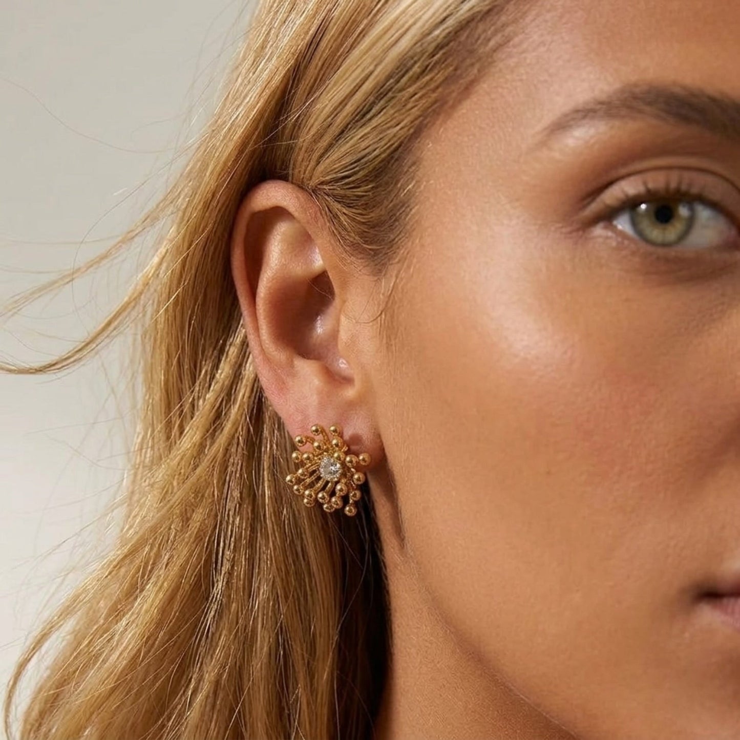 BEHI MILANO Artymanos Earrings — close-up of model wearing gold sunburst crystal stud earring