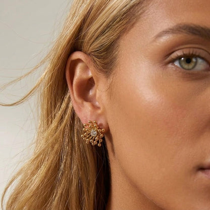BEHI MILANO Artymanos Earrings — close-up of model wearing gold sunburst crystal stud earring