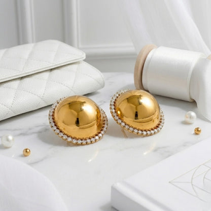 BEHI MILANO Audrey Earrings — pair of gold dome halo studs styled on marble next to luxury white handbag
