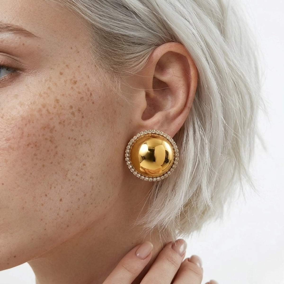 BEHI MILANO Audrey Earrings — detailed close-up of gold dome crystal stud earring on model's ear