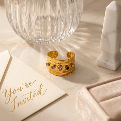 BEHI MILANO Azzu Ring — open band gold ring displayed on beige stone with ribbed glass cup