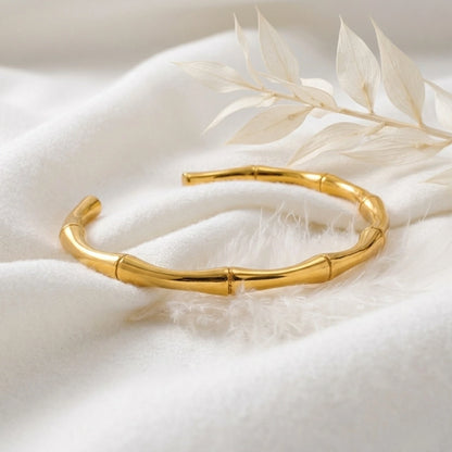 BEHI MILANO Bamboo Bracelet — 18k gold open cuff displayed on soft white fabric