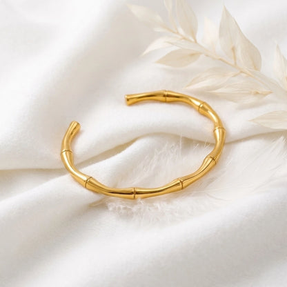 BEHI MILANO Bamboo Bracelet — gold bamboo bangle resting on luxury white silk fabric