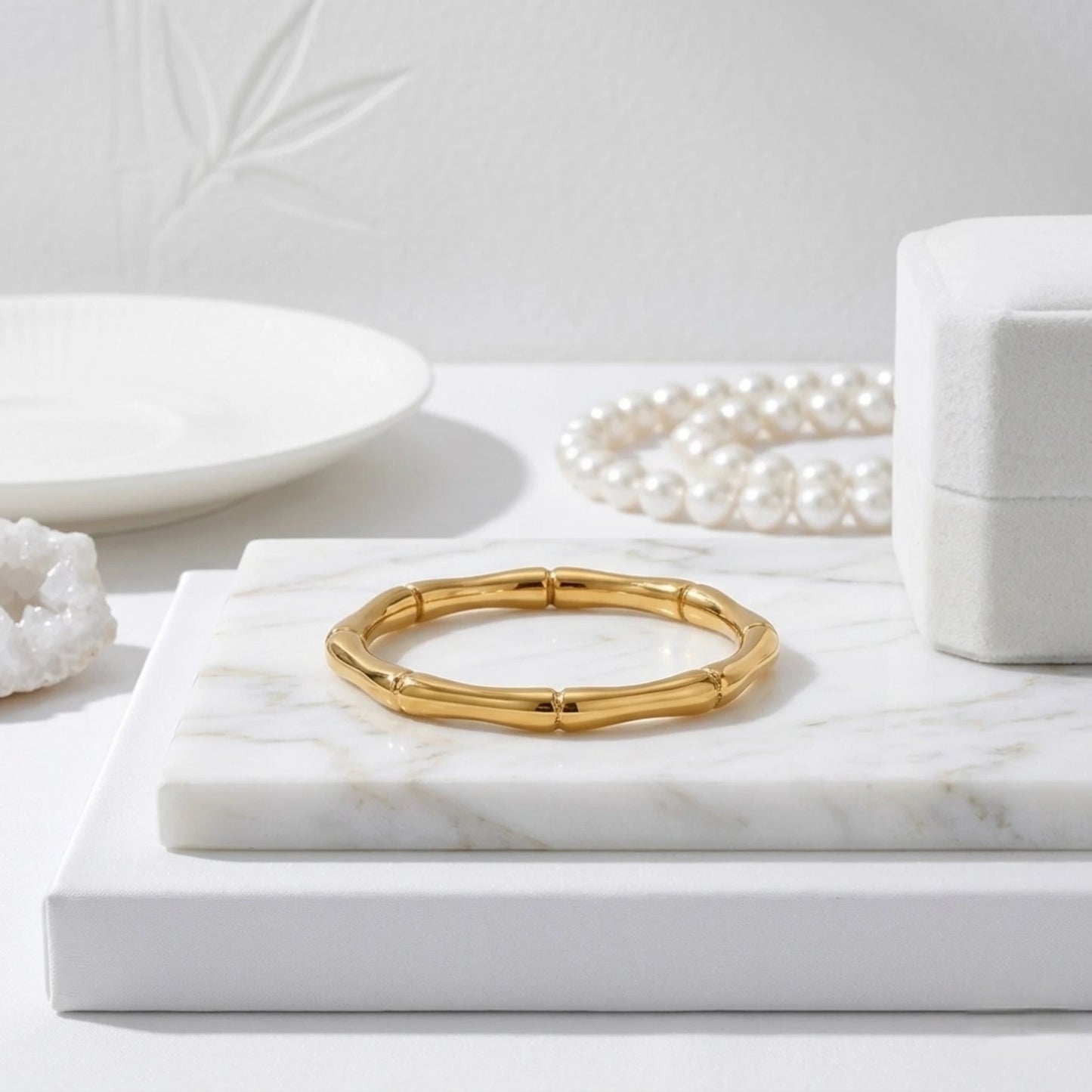 BEHI MILANO Bamboo Ring — 18k gold-plated ring on white marble pedestal with pearl necklace