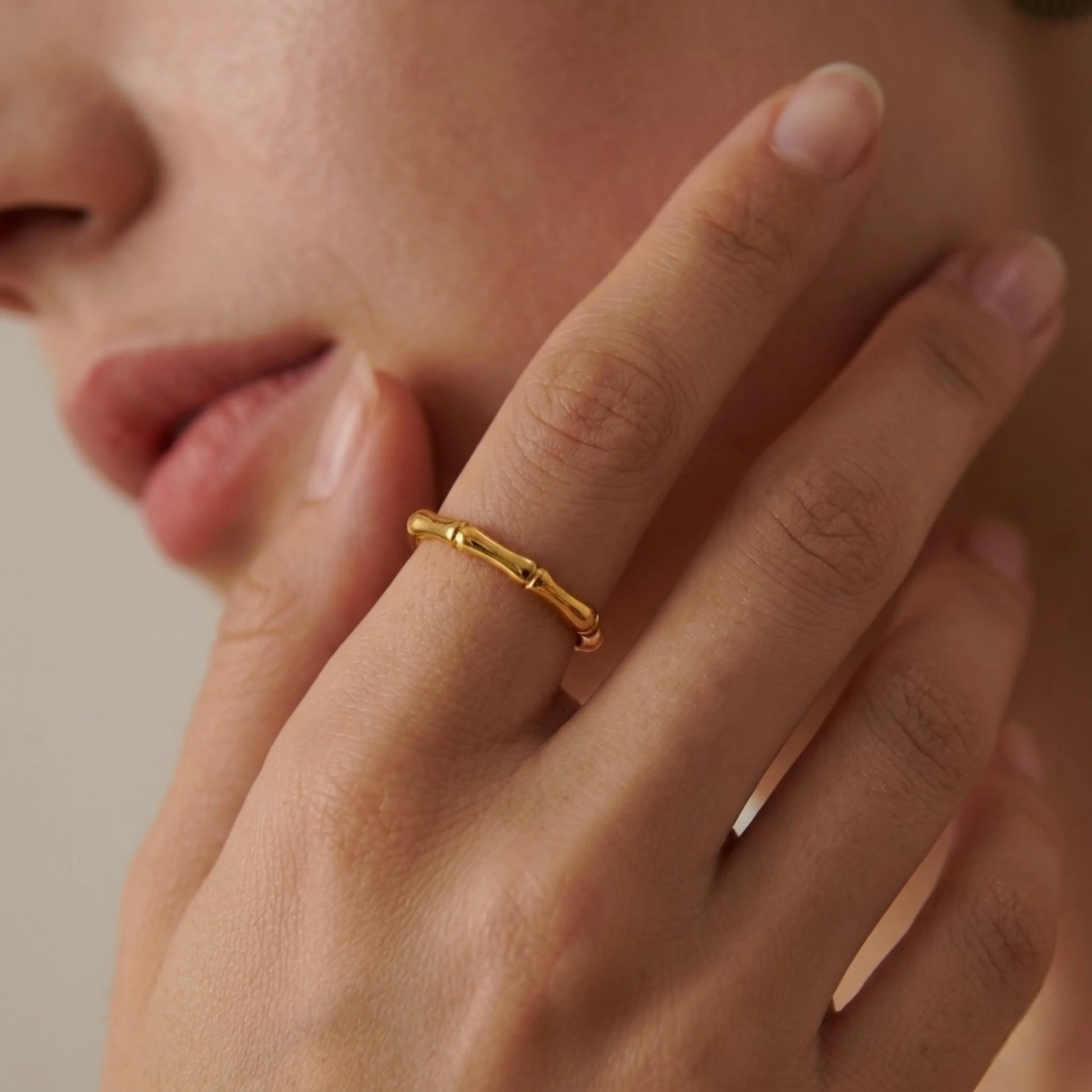 BEHI MILANO Bamboo Ring — close-up of model holding hand near neck wearing delicate gold ring