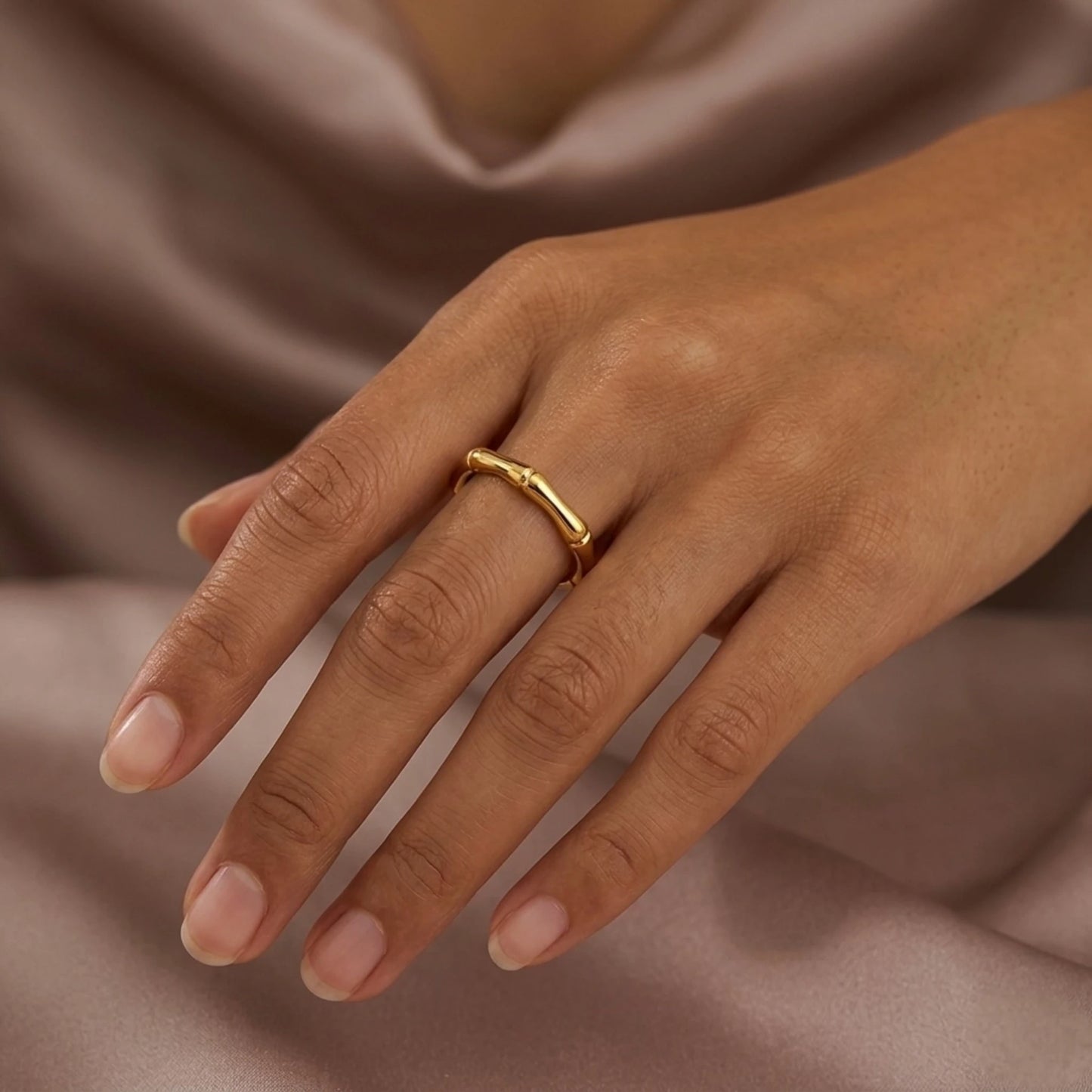 BEHI MILANO Bamboo Ring — model hand resting on soft satin fabric wearing gold ring