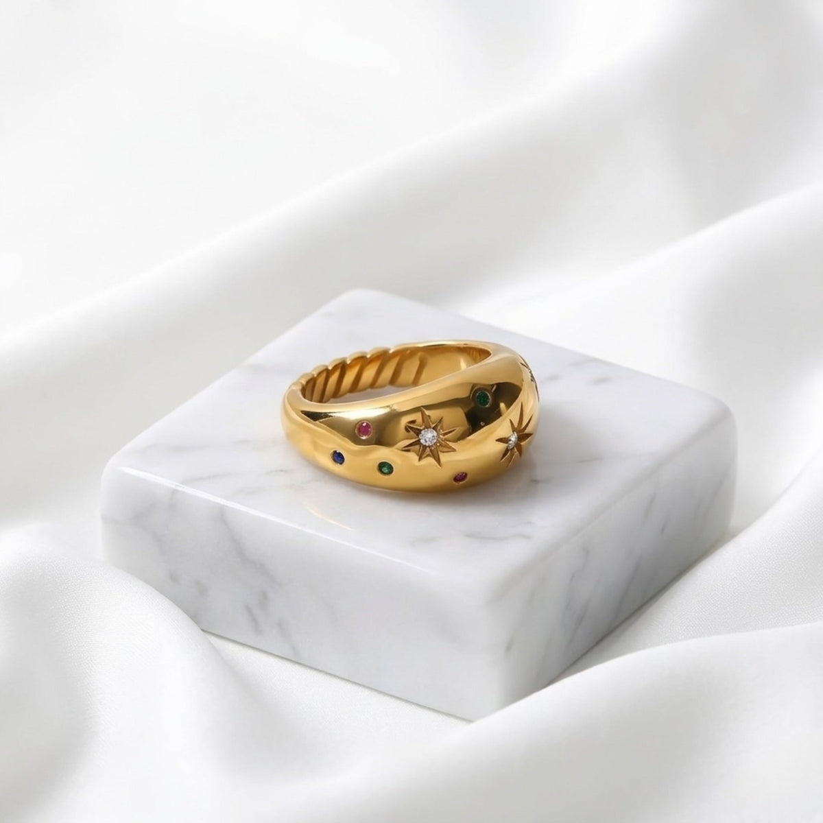 BEHI MILANO Camila Ring — close-up of gold celestial ring on white marble pedestal