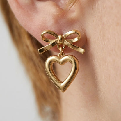 BEHI MILANO Cara Earrings — detailed ear close-up of 18k gold-plated bow and heart drop earring