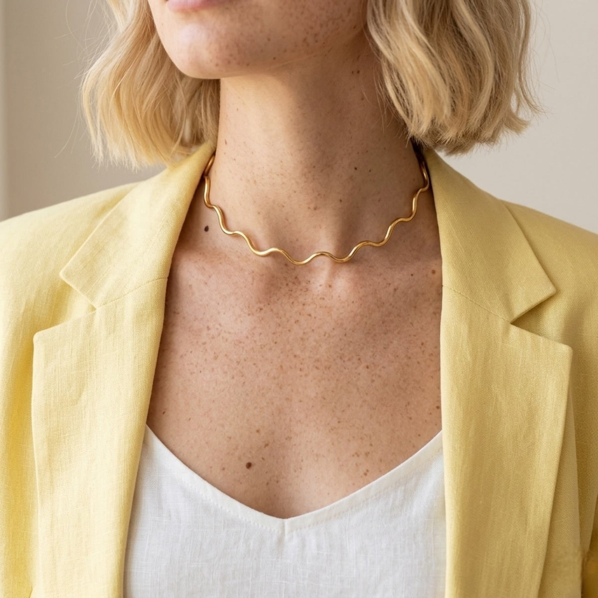 BEHI MILANO Carla Choker — front view of gold wave neck wire on model in white top and yellow jacket