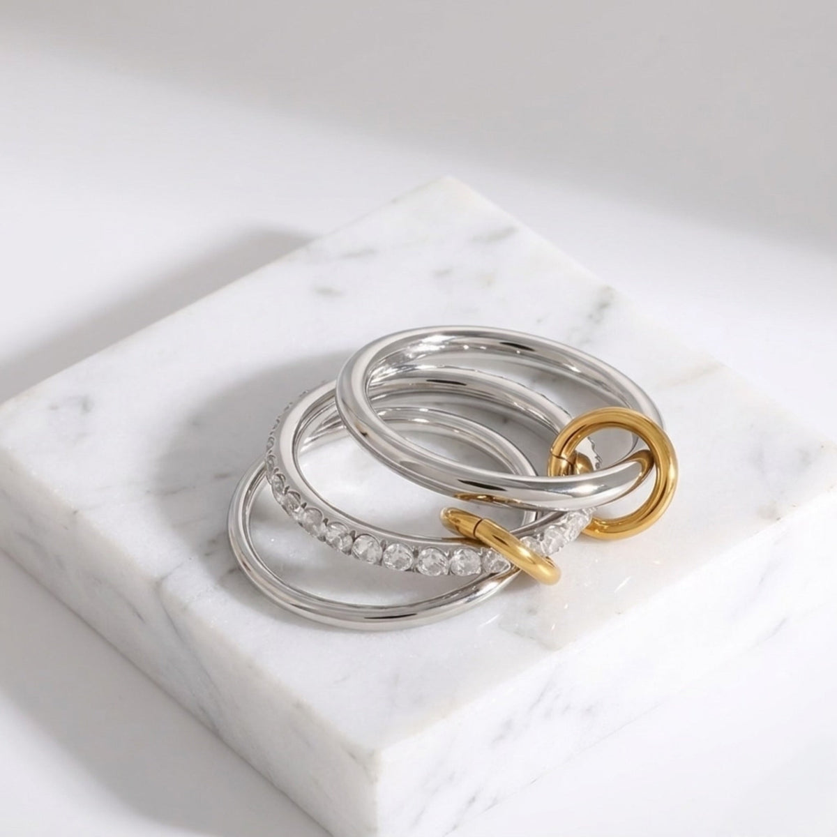 BEHI MILANO Carlita Ring — multi-finger connected ring folded into stack on white marble block