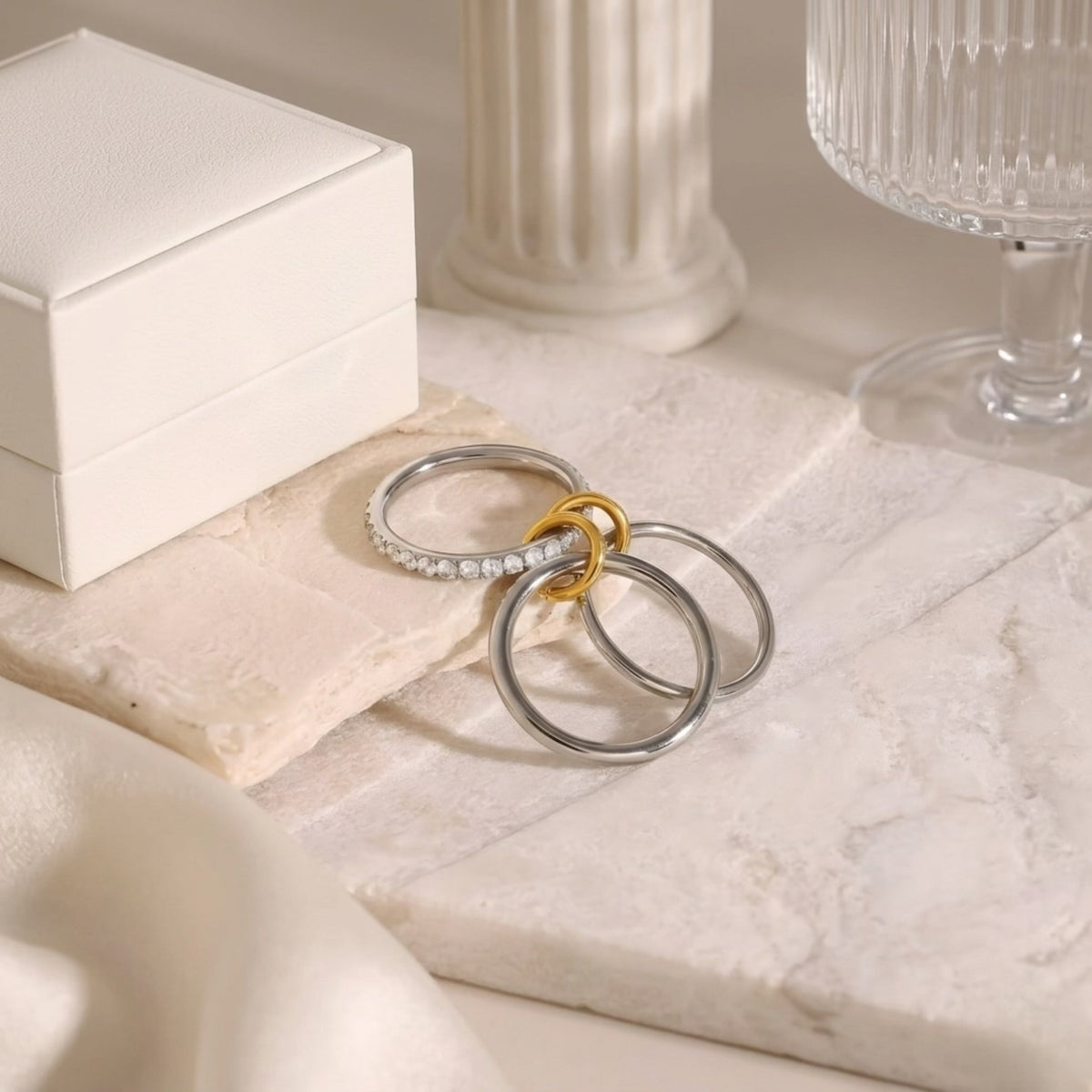 BEHI MILANO Carlita Ring — multi-finger gold and silver pave CZ ring resting on travertine stone