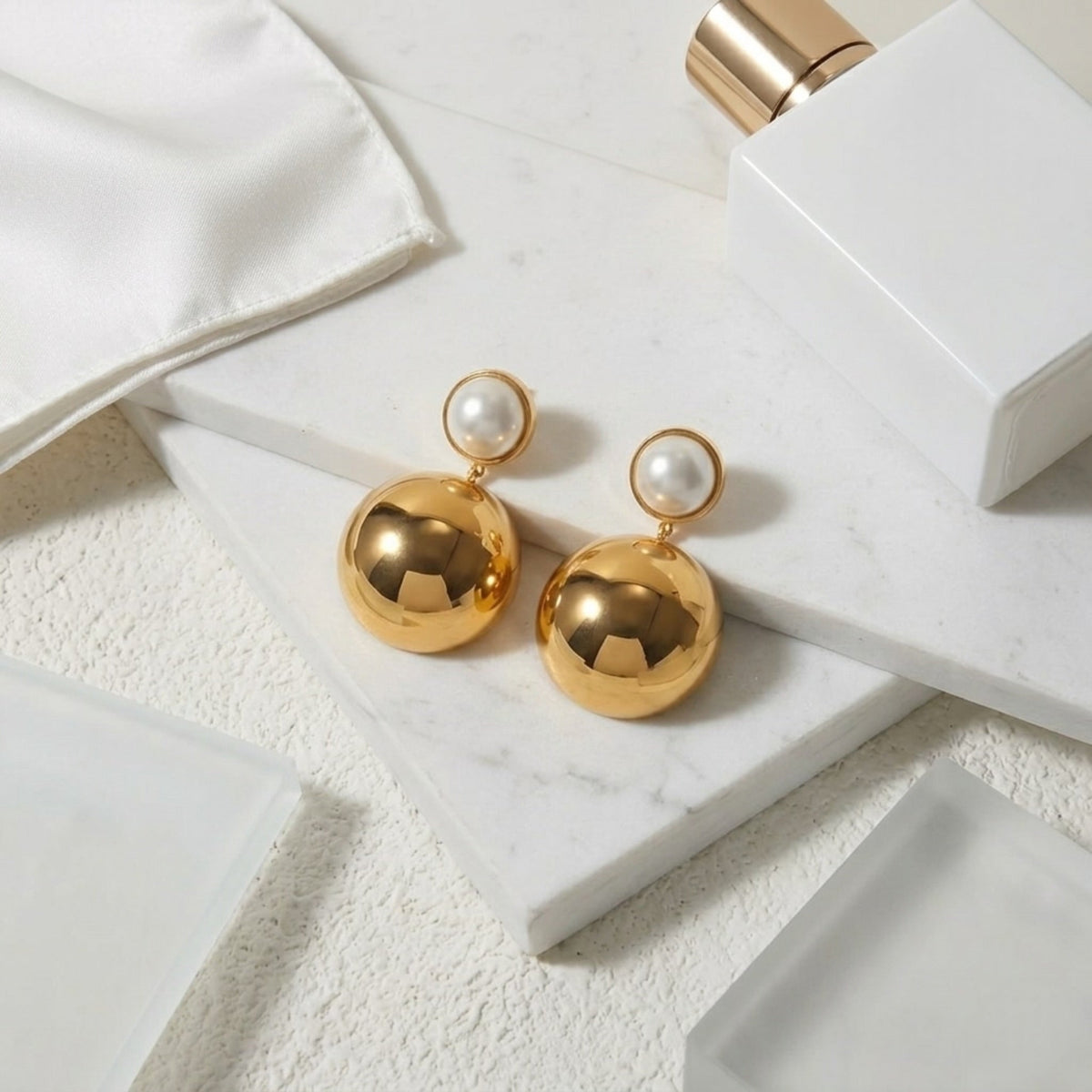 BEHI MILANO Carollina Earrings — close-up of mirror-polished gold sphere earrings on marble