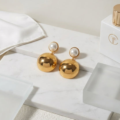 BEHI MILANO Carollina Earrings — gold and pearl statement drop earrings on marble next to luxury perfume