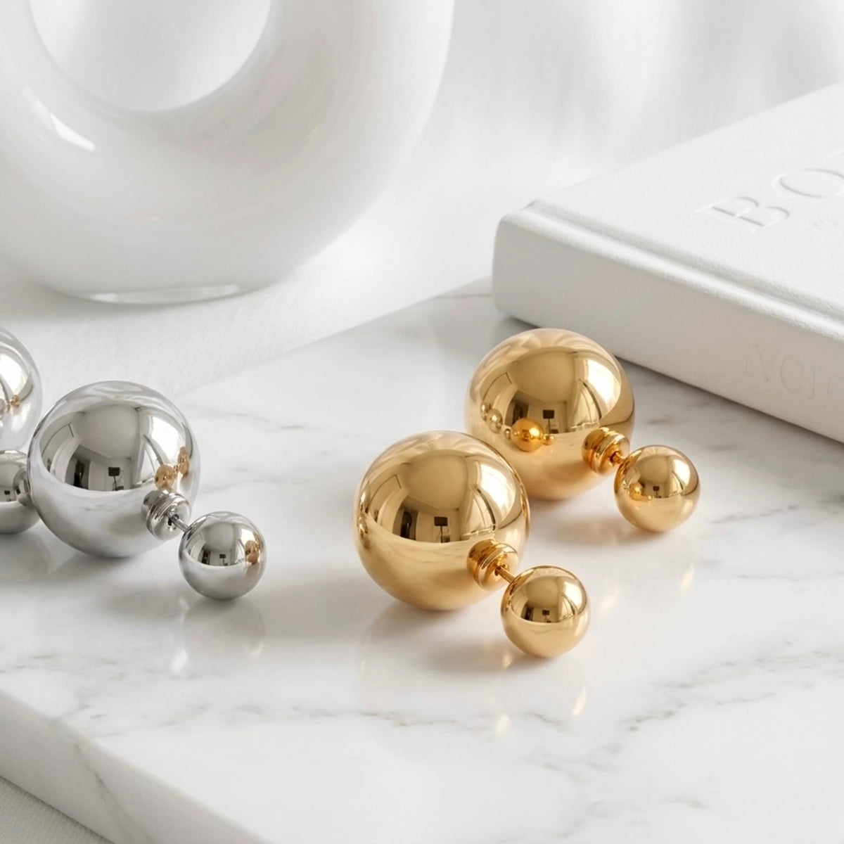 BEHI MILANO Chic Earrings — pair of gold and silver double ball studs on marble tray