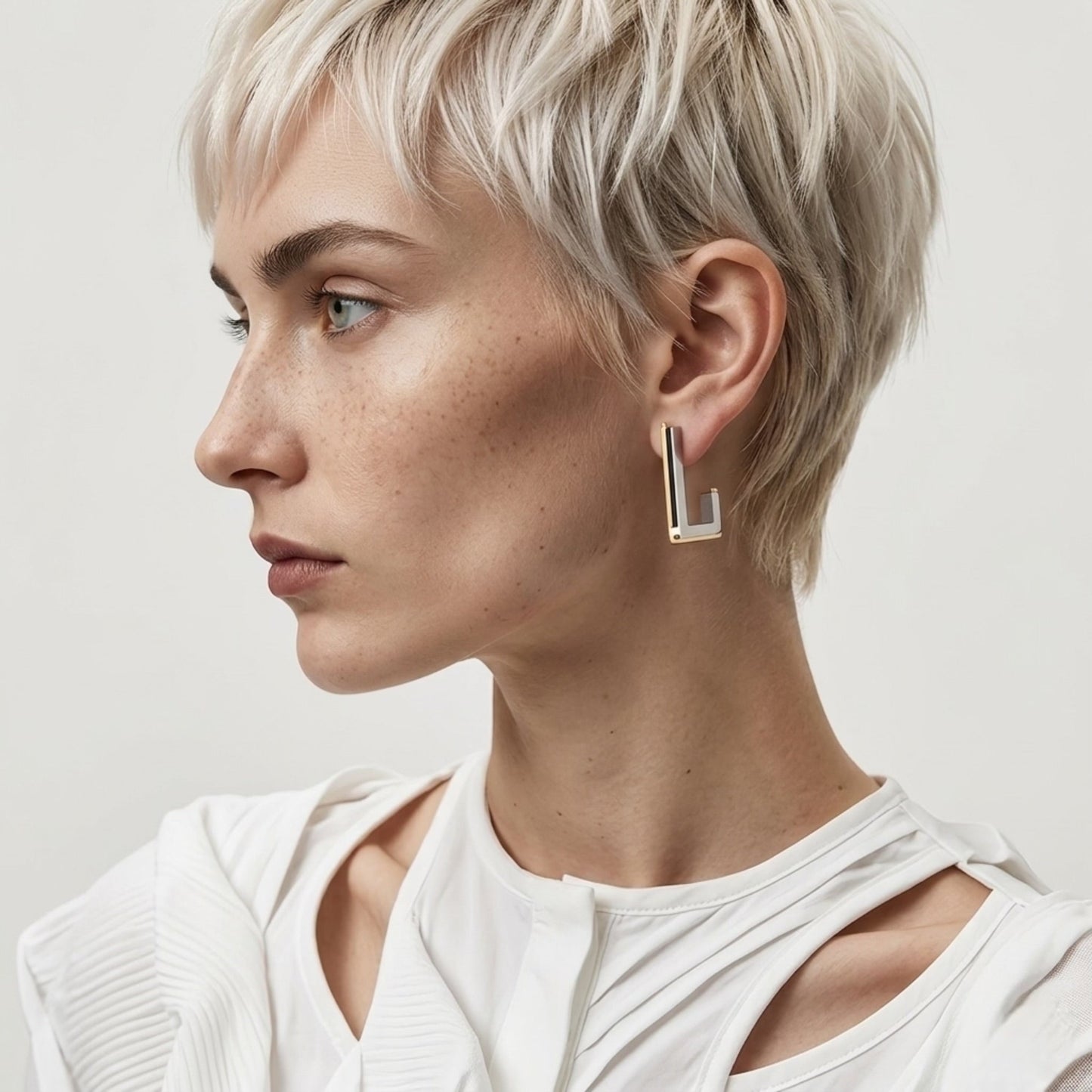 BEHI MILANO Cindy Earrings — model with blonde crop hairstyle wearing silver and gold rectangular drop earrings