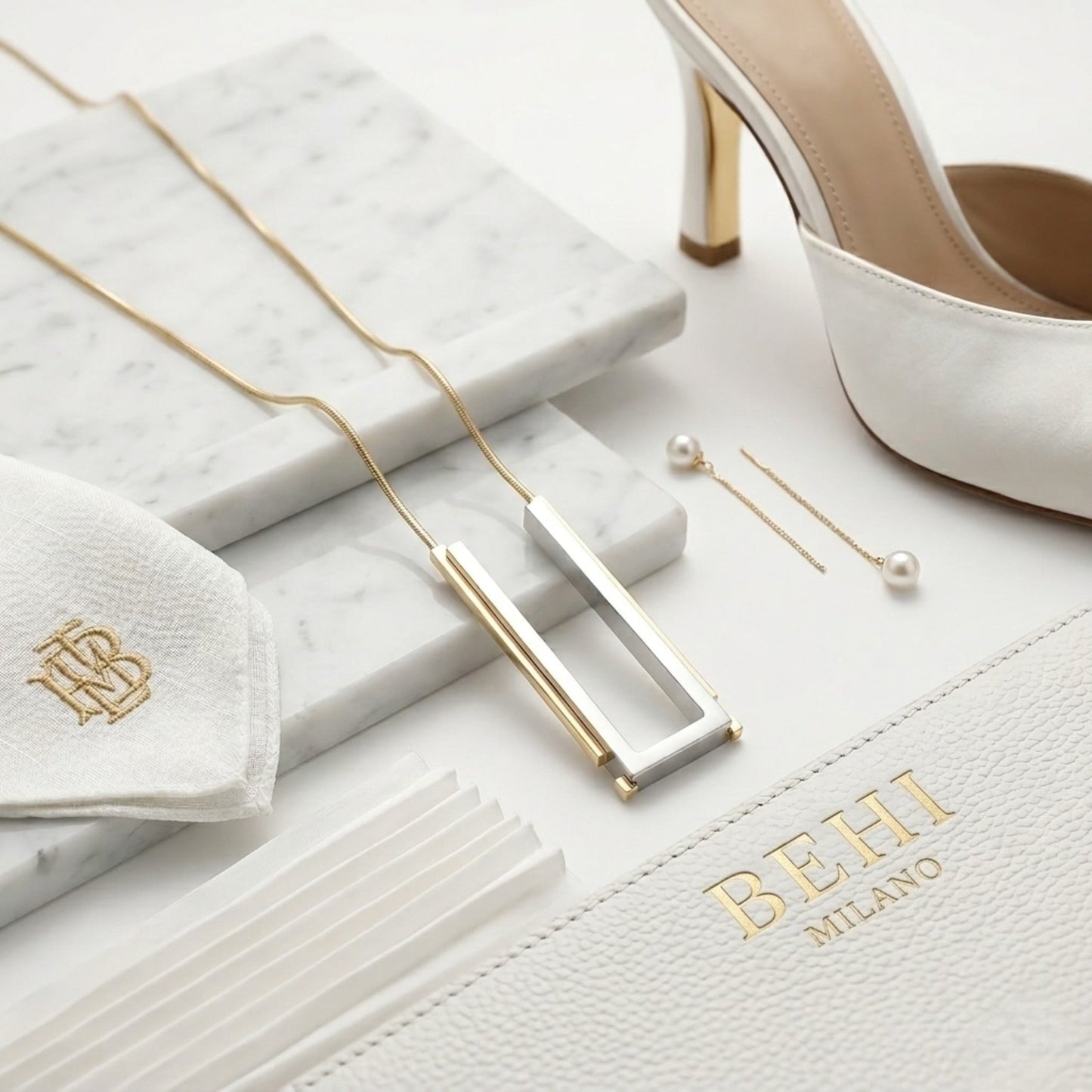 BEHI MILANO Cindy Necklace — two-tone architect pendant with luxury brand pouch on marble pedestal