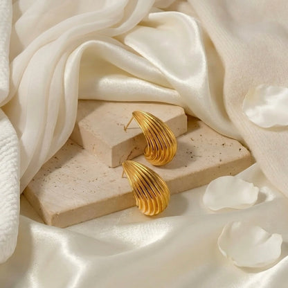 BEHI MILANO Claire Earrings — gold ribbed studs on beige stone block with white flower petals