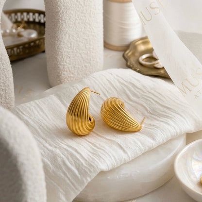 BEHI MILANO Claire Earrings — gold ribbed drop earrings on draped white silk fabric