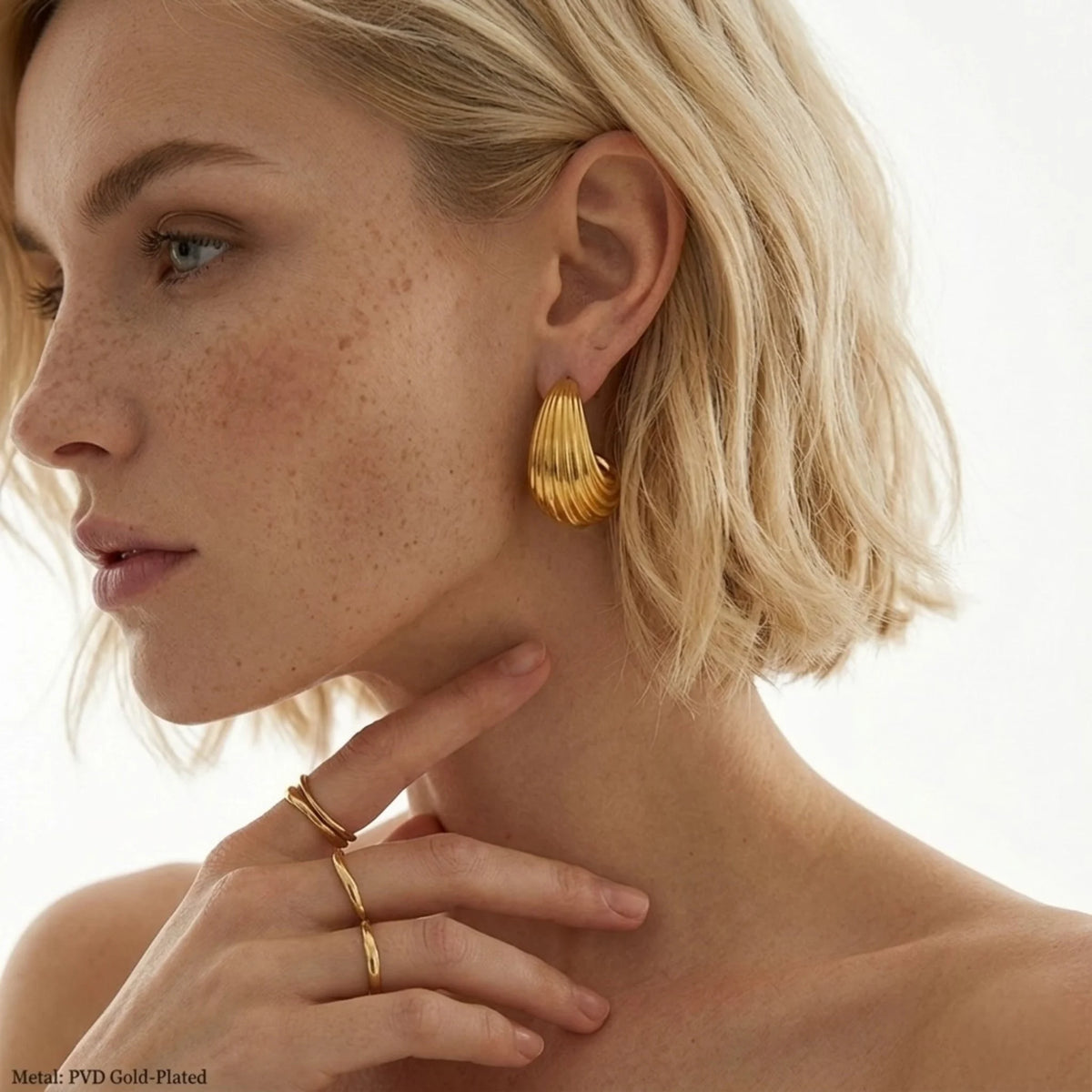 BEHI MILANO Claire Earrings — close-up of model ear wearing 18k gold fluted croissant earrings