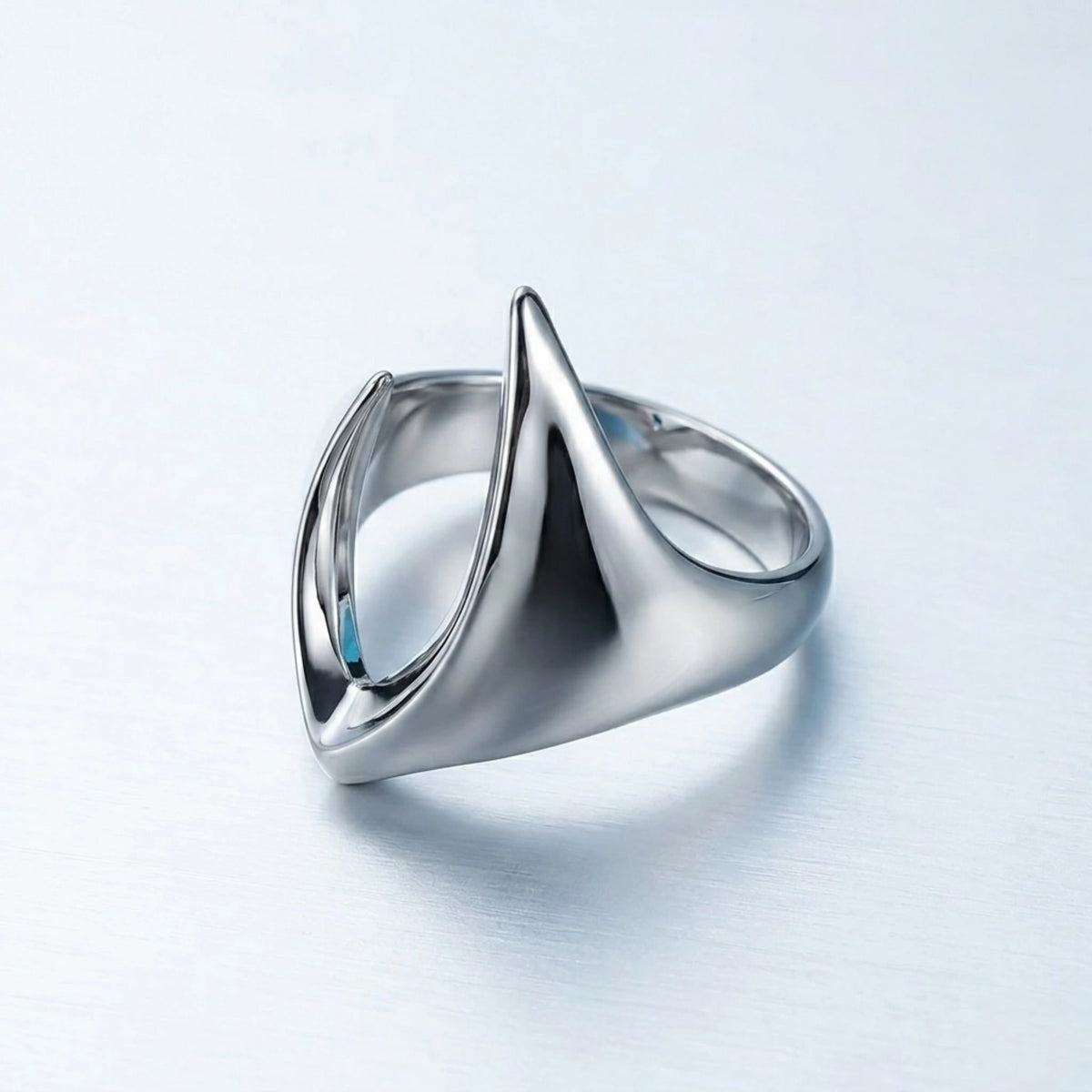 BEHI MILANO Clarissa Ring — silver-toned gothic blade sculptural ring on light blue reflective background