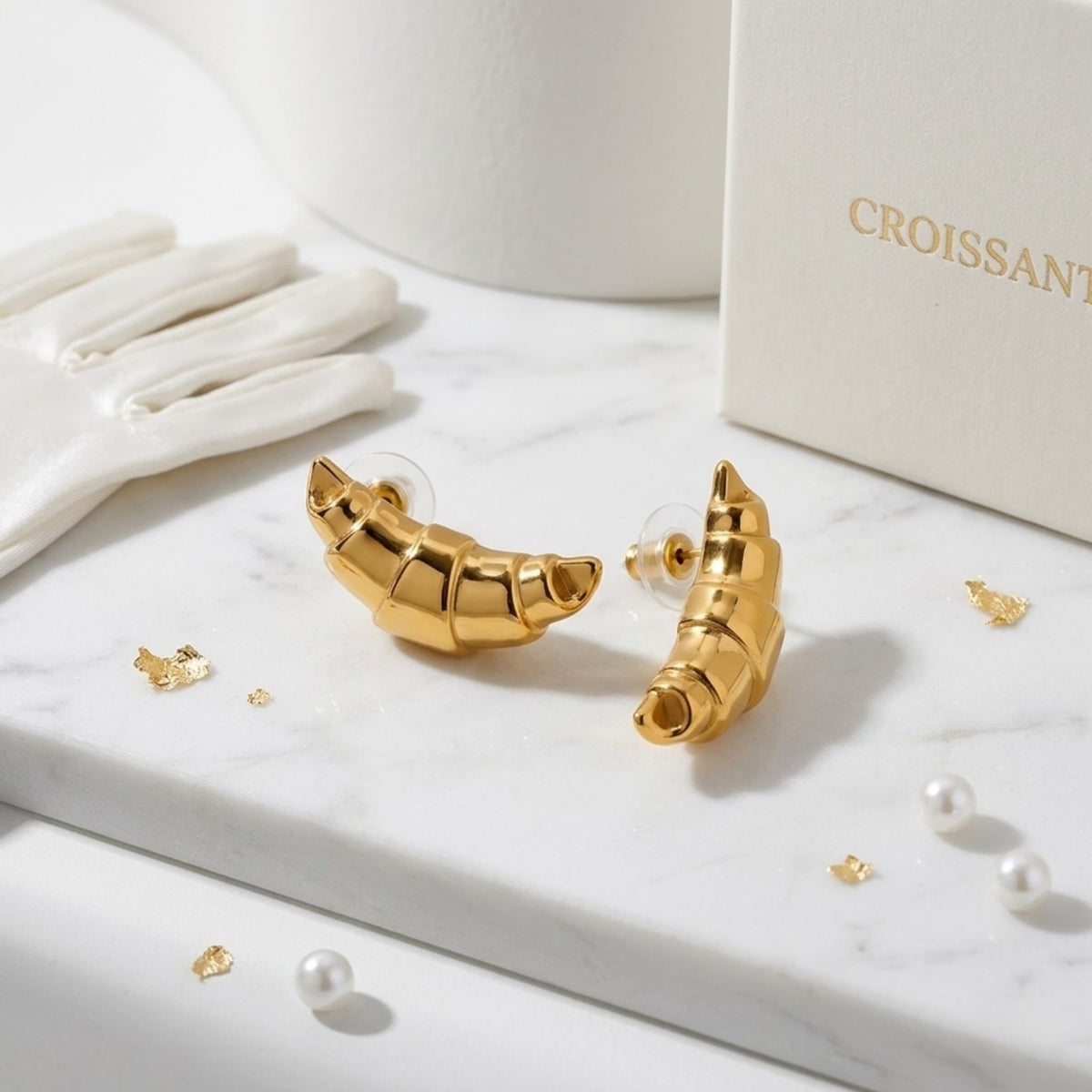 BEHI MILANO Cornetto Earrings — 18k gold crescent studs displayed with white satin gloves and croissant jewelry box
