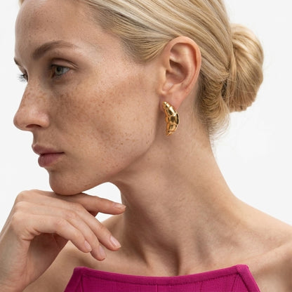 BEHI MILANO Cornetto Earrings — model with slick hair bun wearing 18k gold crescent statement studs