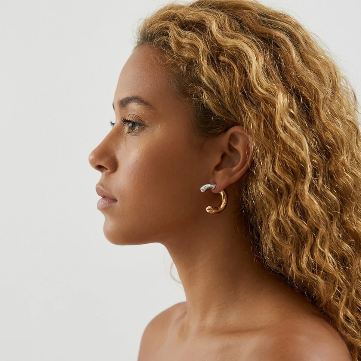 BEHI MILANO Dafne Earrings — profile view of model wearing two-tone gold and chrome accent drop hoop earrings