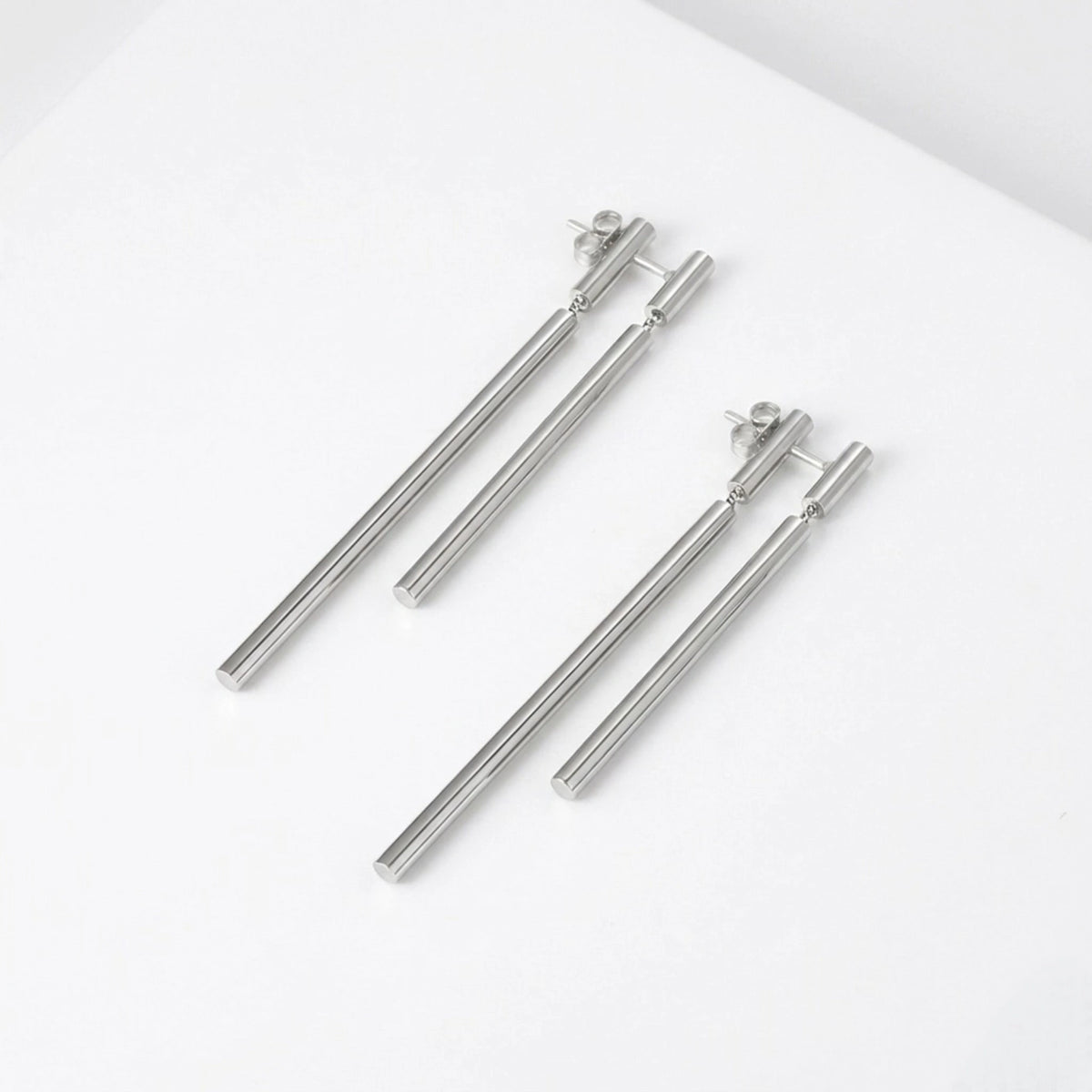 BEHI MILANO Deffi Earrings — silver stainless steel double rod drop earrings on white surface