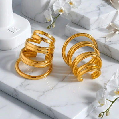 BEHI MILANO Denyse Ear Cuffs — gold stacked helix cuffs on marble slab with white orchids