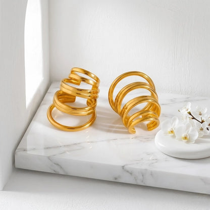 BEHI MILANO Denyse Ear Cuffs — gold spiral non-pierced ear cuffs displayed on marble pedestal